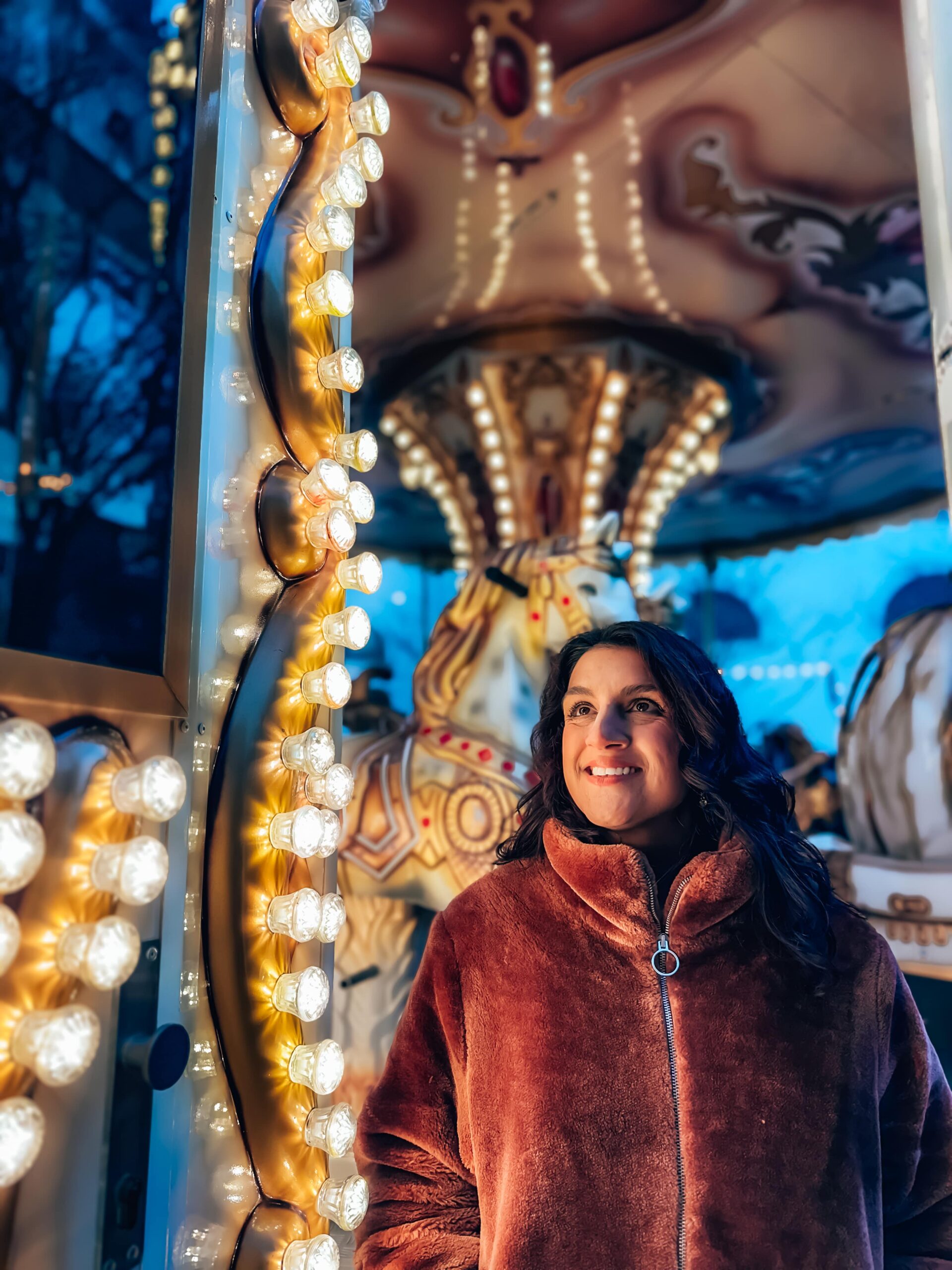Brno christmas markets guide - city break guide - girl's face lit up by christmas market carousel